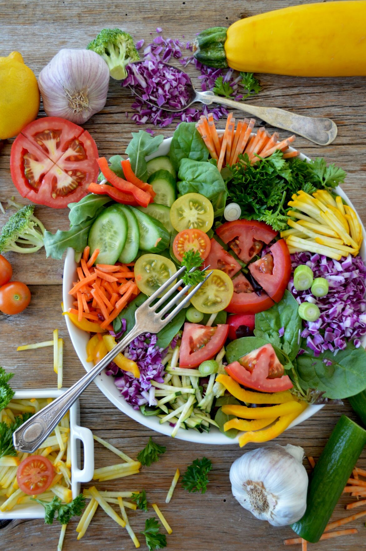 Sliced fresh summer vegetables and greens arranged on a white ceramic plate