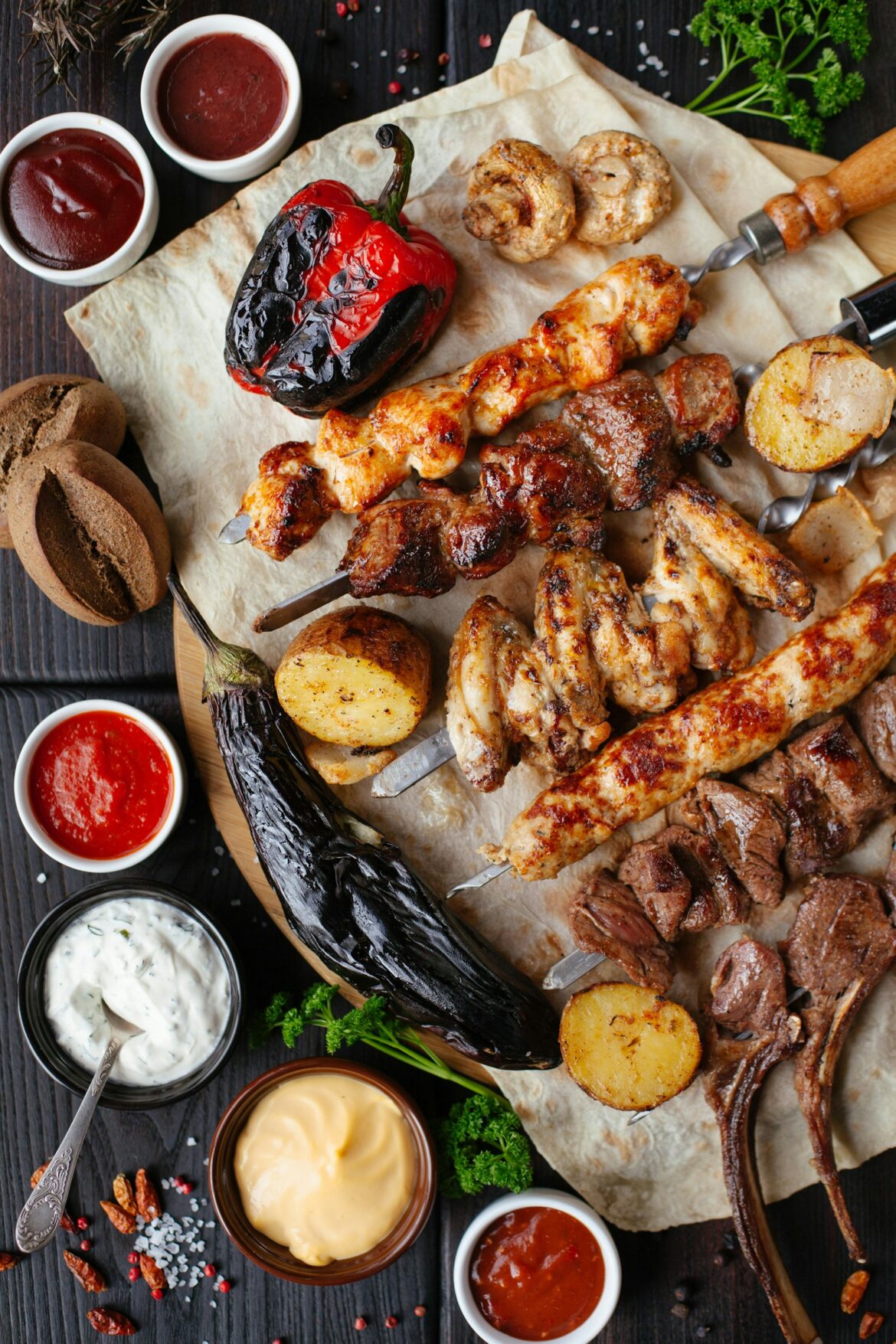 Platter of grilled meats skewers and roasted vegetables with dipping sauces