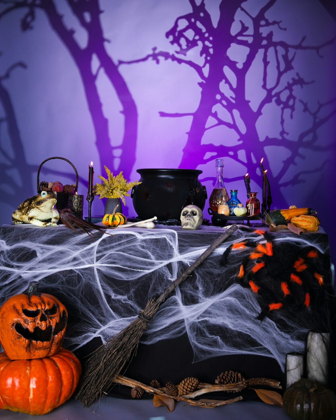 Halloween party table with a cauldron, skull, potion bottles, cobwebs and jack o lanterns