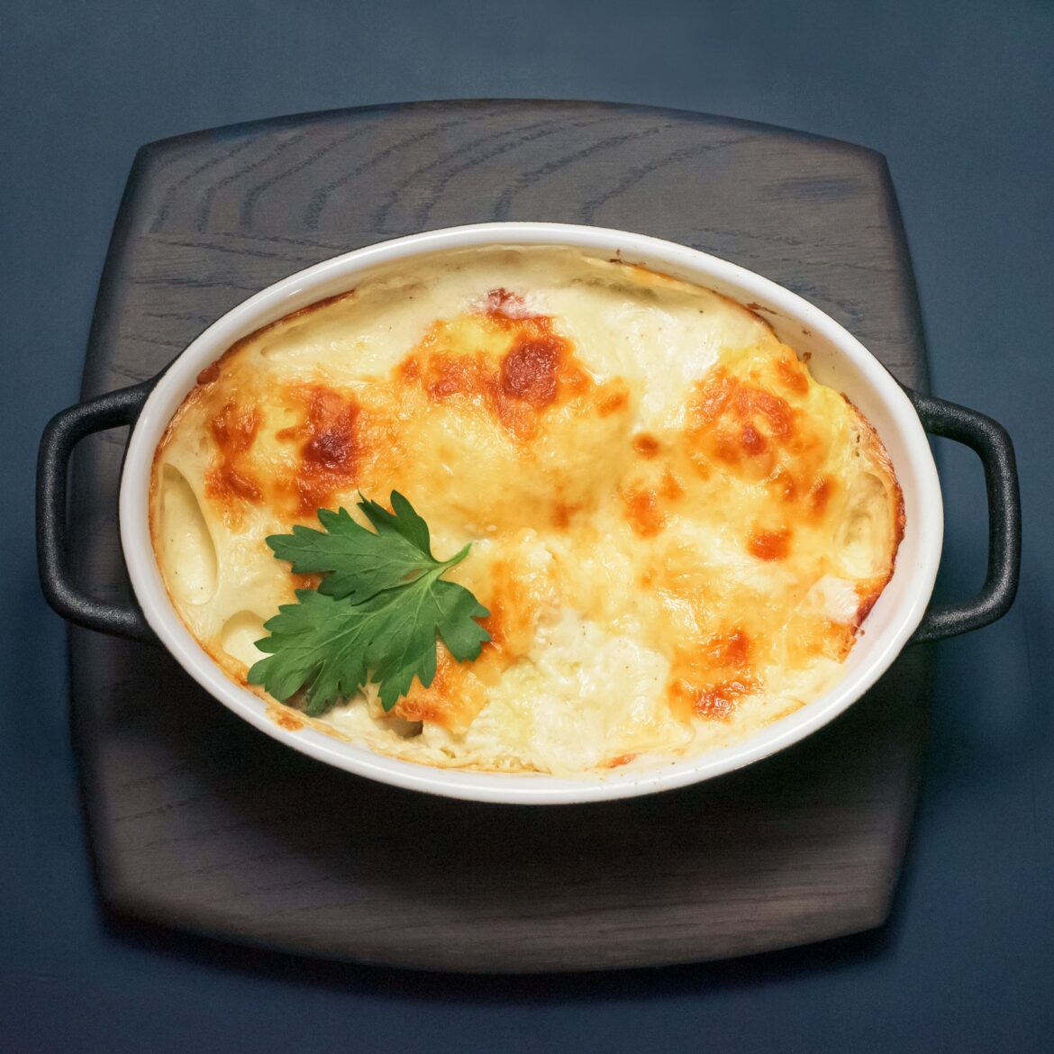 Baked cheesy casserole in a dish topped with fresh parsley