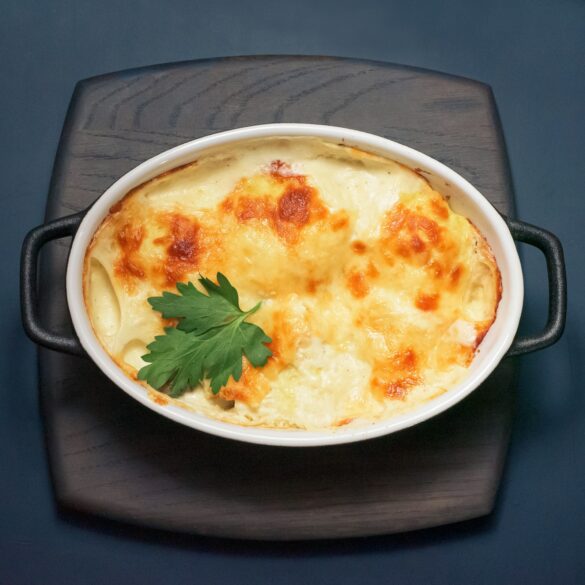 Baked cheesy casserole in a dish topped with fresh parsley