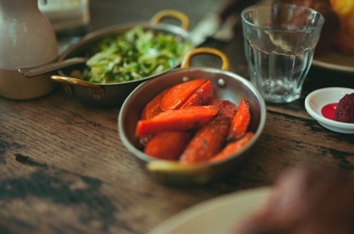 Roasted carrots and fresh salad served in metal bowls on a table