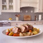 Slow cooker pork shoulder in tender chunks with potatoes, carrots and gravy on a white platter