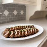Sliced slow cooker pork tenderloin with brown sugar garlic glaze and parsley on a white platter