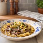 Crockpot beef and noodles with shredded beef and egg noodles in a cream bowl with a blue floral rim