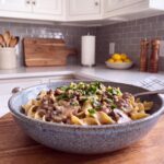 Ground beef stroganoff with egg noodles and mushrooms in a creamy sauce in a speckled blue stoneware bowl